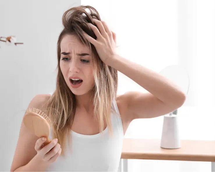 Besorgte Frau mit Haarbürste bei Haarausfall in Artikel über Haarausfall bewältigen