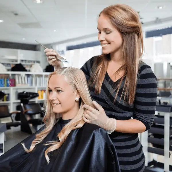 Haarstylist trägt mit Alfaparf Milano BB Bleach High Lift 9 Tones Haarfärbecreme auf
