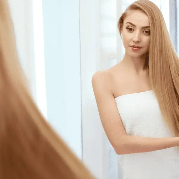 Frau im Handtuch schaut in Spiegel mit Alfaparf Milano Keratin Therapy Lisse Design Detangling Cream